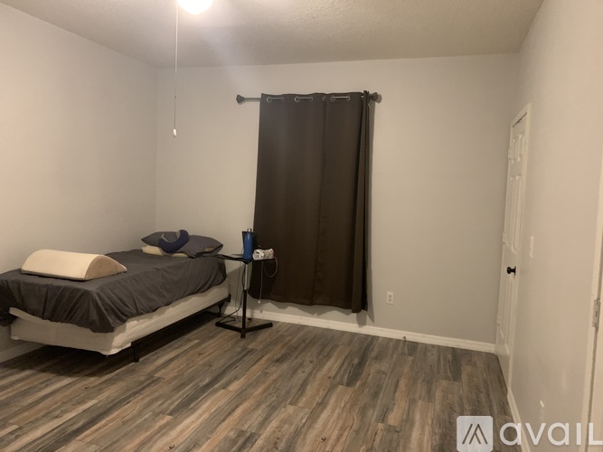A bedroom with a bed, nightstand, and a window with a curtain.