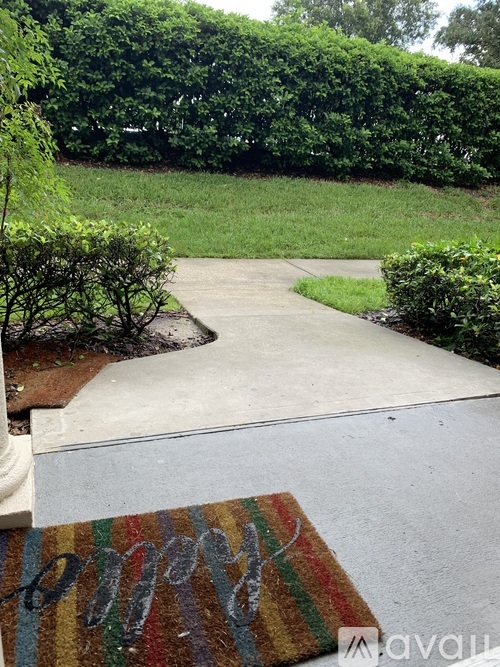 A concrete walkway leads to a grassy area with bushes on either side.