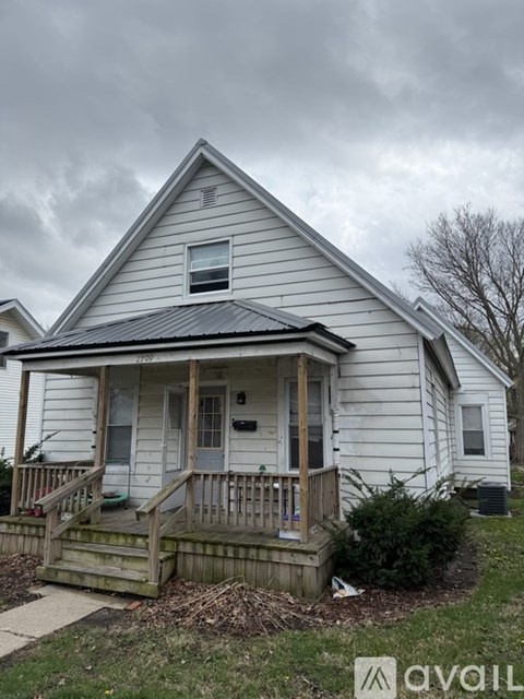 A small white house with a porch and a dark roof.