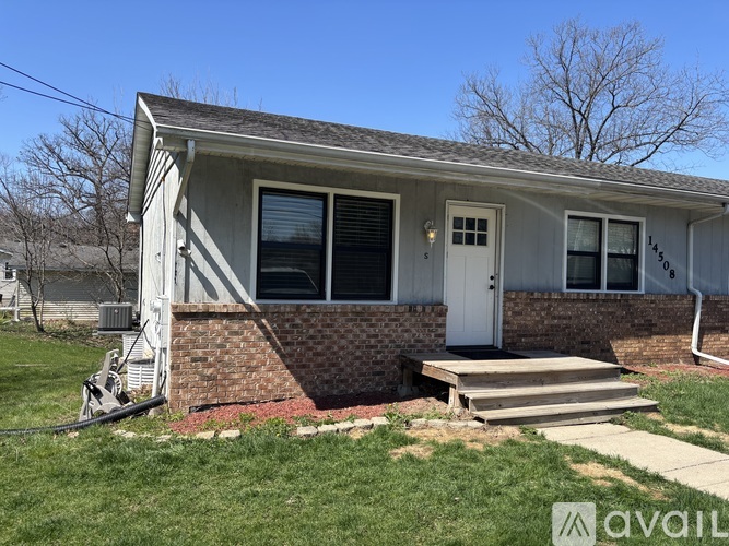 A house with a white door and a brick base is available for rent.