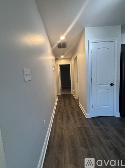 A hallway with a white door and wooden floors.