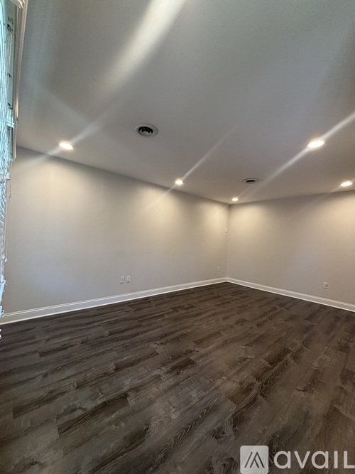 A room with wooden flooring and white walls.