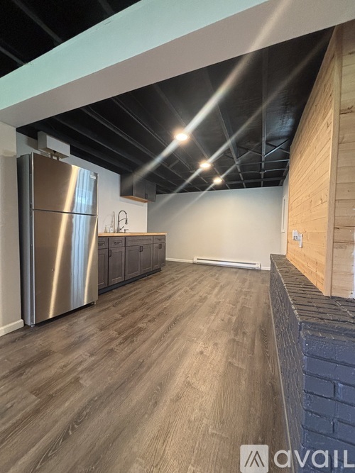 A kitchen with a stainless steel refrigerator and wooden flooring.