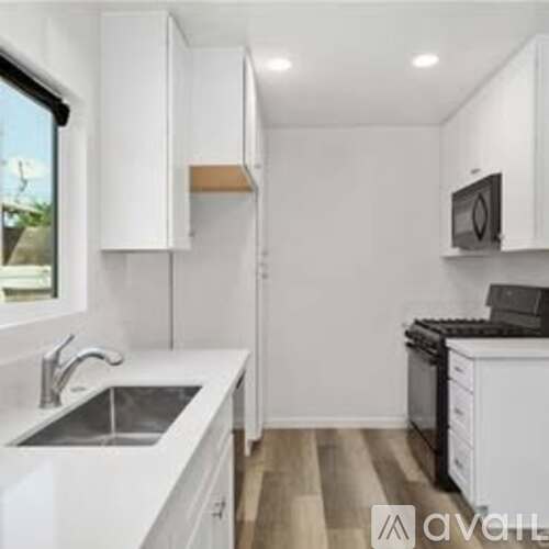 A kitchen with white cabinets and a black microwave.