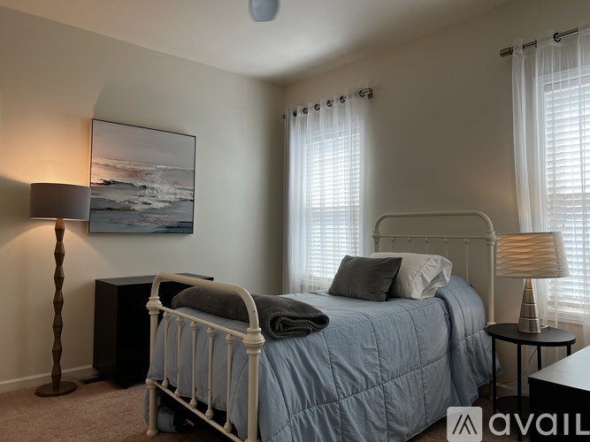 A bedroom with a large bed and a painting on the wall.