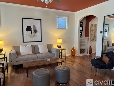 A living room with a grey couch, a coffee table, and a painting on the wall.