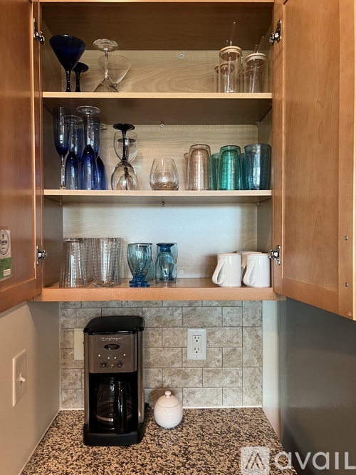 A kitchen cabinet with glasses and cups on the shelf.