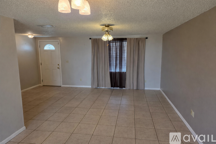 A room with beige walls and a tiled floor with a door and window.