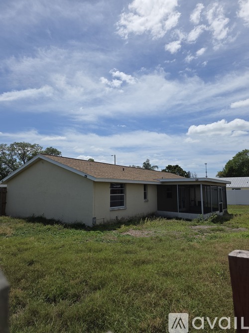 A house with a brown roof and a white wall is surrounded by grass.