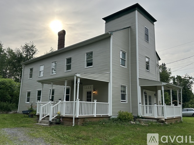 A two-story house with a porch and a chimney.