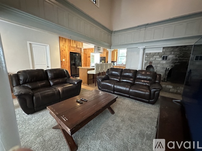 A living room with two black leather couches and a wooden coffee table.