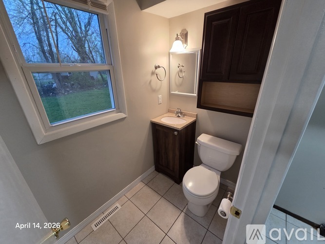 A bathroom with a toilet, sink, and window.