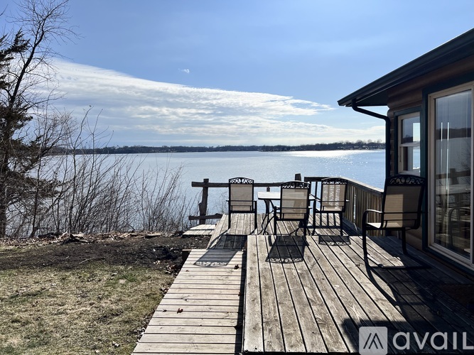 A wooden deck overlooks a lake with a clear blue sky above.
