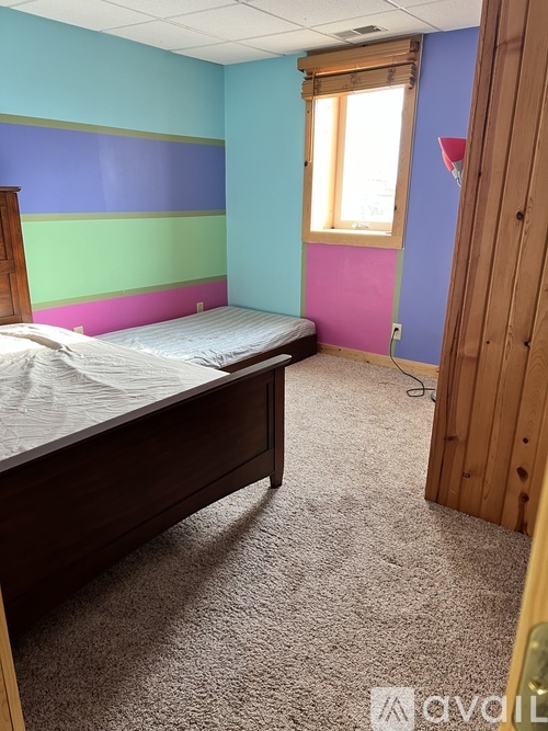 A bedroom with a bed, carpet, and a window.