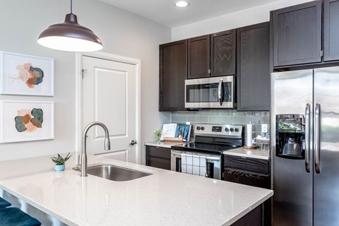 A modern kitchen with dark brown cabinets and stainless steel appliances.