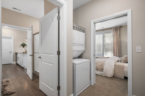 A white door is open to a bedroom with a bed and a window.