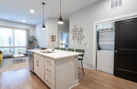 A modern kitchen with white cabinets and a black door.