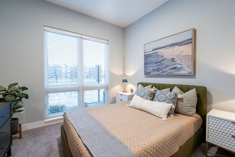 A bedroom with a large bed and a painting on the wall.