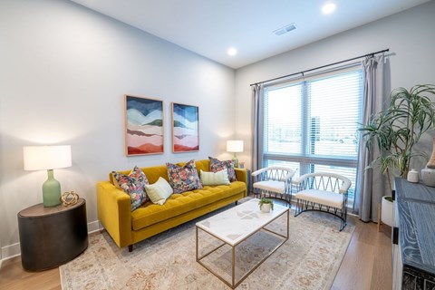 A living room with a yellow couch and a coffee table.