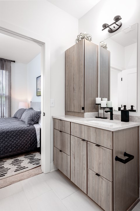 A modern bedroom with a large bed and a vanity with a mirror.