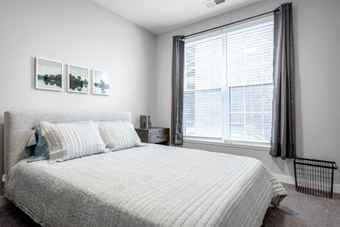 A bedroom with a large bed and two pictures on the wall.