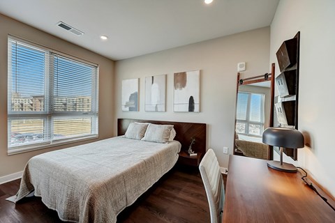 A bedroom with a large bed and a desk with a chair.