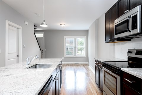A kitchen with a marble countertop and dark wood cabinets.