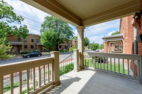 A view from a porch looking out at a street with cars and houses.