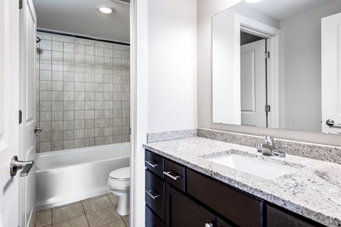 A bathroom with a white toilet and a marble counter top.