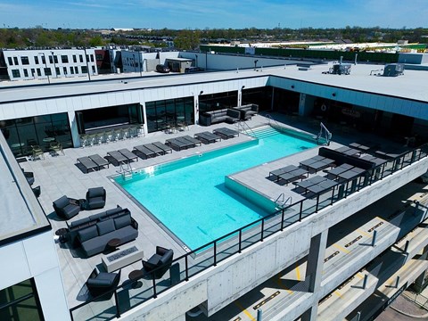A large swimming pool with lounge chairs and a concrete deck.