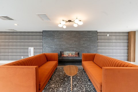 A modern living room with orange couches and a fireplace.