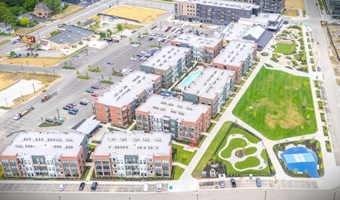 An aerial view of apartment buildings with a parking lot and a green space with a playground.