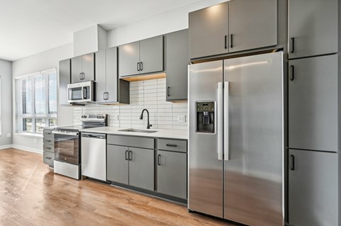 A modern kitchen with stainless steel appliances and wooden floors.