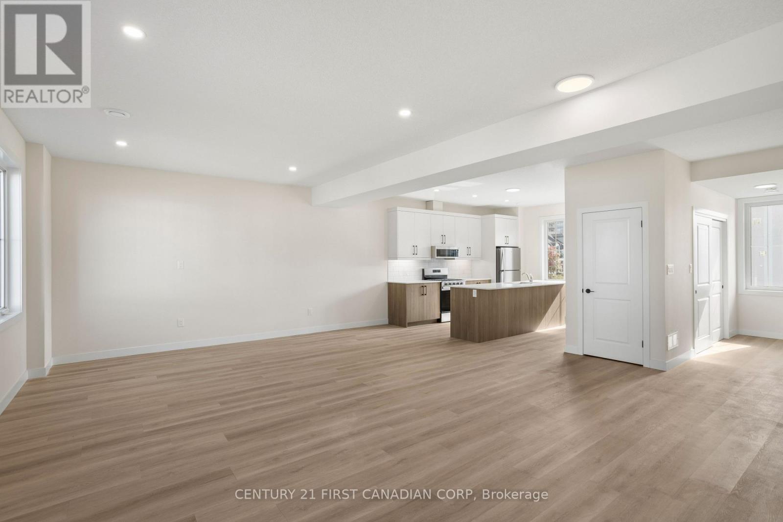 A spacious room with wooden flooring and white walls.