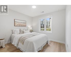 A spacious room with wooden flooring and two windows.