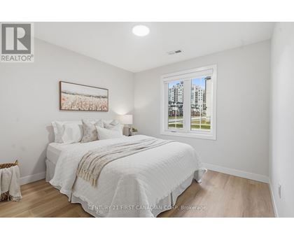 A spacious room with wooden flooring and two windows.