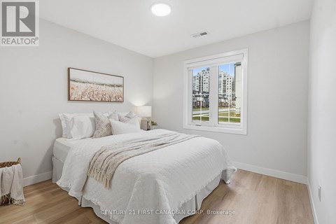 A spacious room with wooden flooring and two windows.
