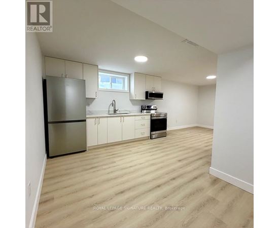 A kitchen with white cabinets and a stainless steel refrigerator.