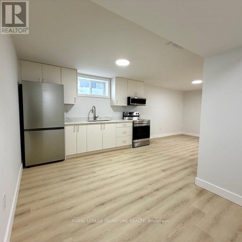 A kitchen with white cabinets and a stainless steel refrigerator.