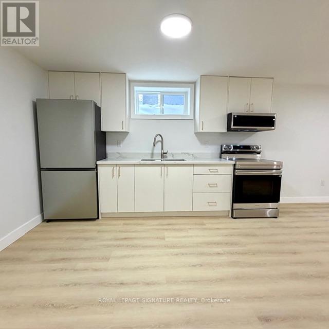 A kitchen with white cabinets and a stainless steel refrigerator.