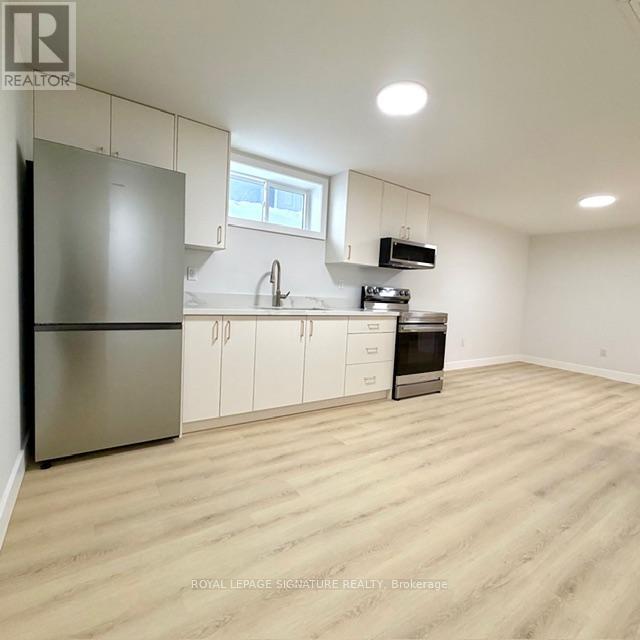 A kitchen with white cabinets and a wooden floor.