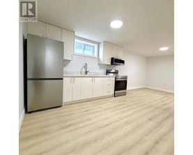A kitchen with white cabinets and a wooden floor.