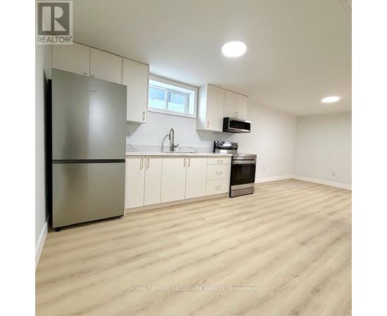 A kitchen with white cabinets and a wooden floor.