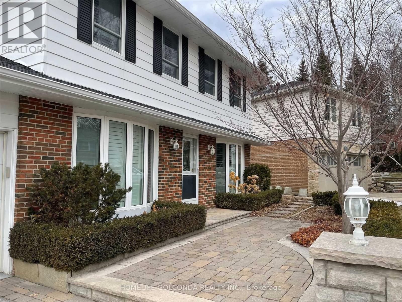 A house with a brick facade and a white roof with a sign that says "REALTOR" on it.