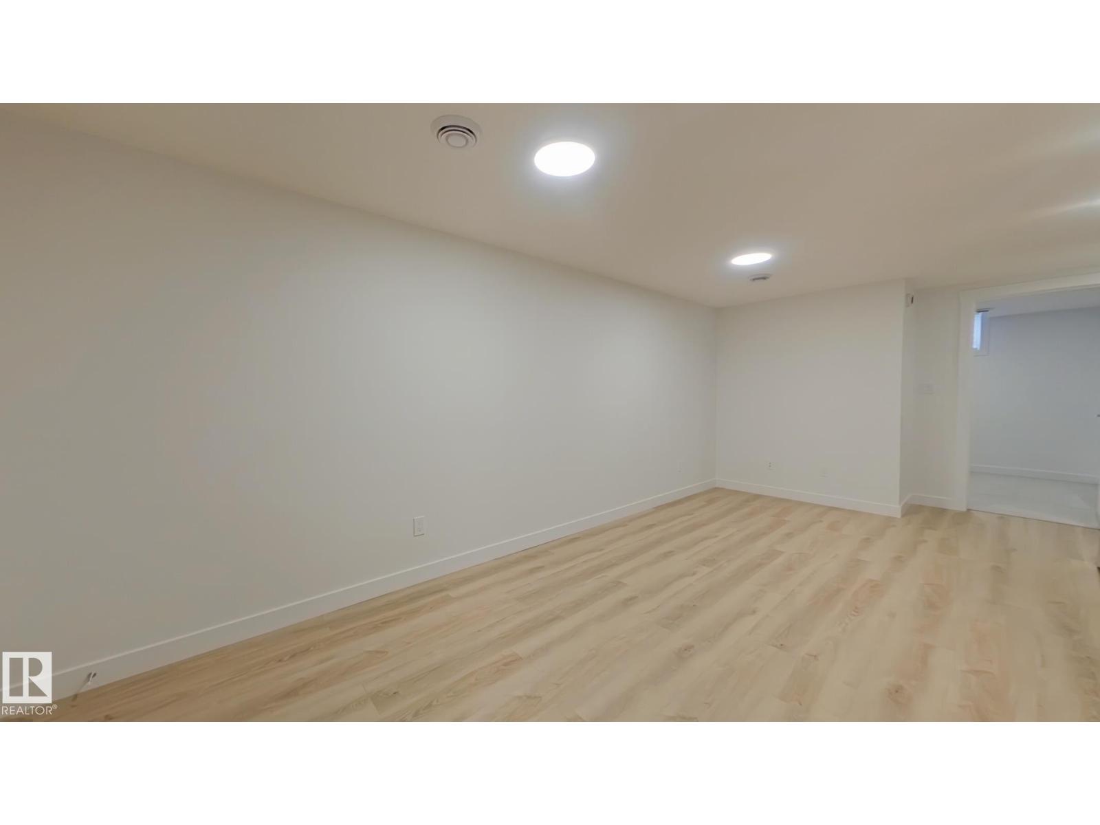 A room with wooden flooring and white walls.