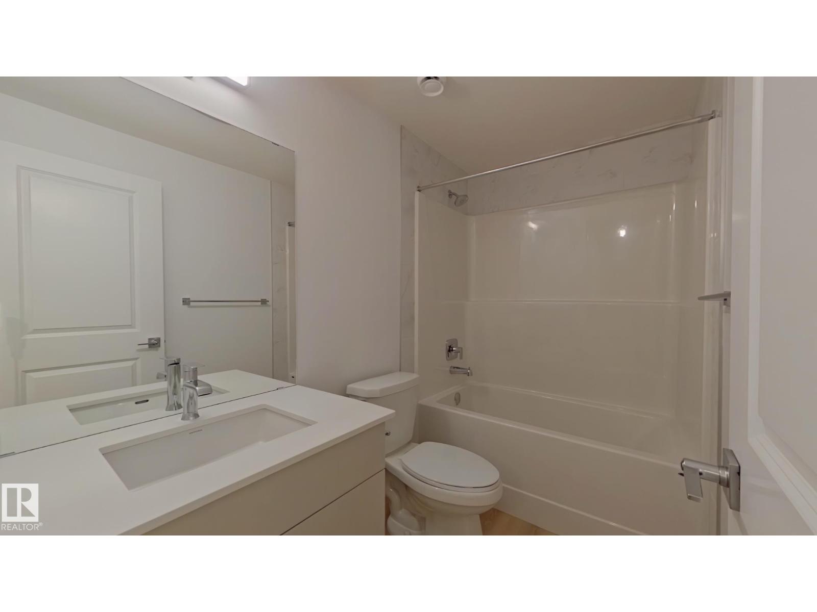 A white bathroom with a toilet, sink, and bathtub.