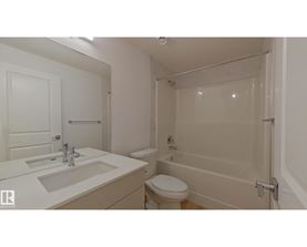 A white bathroom with a toilet, sink, and bathtub.