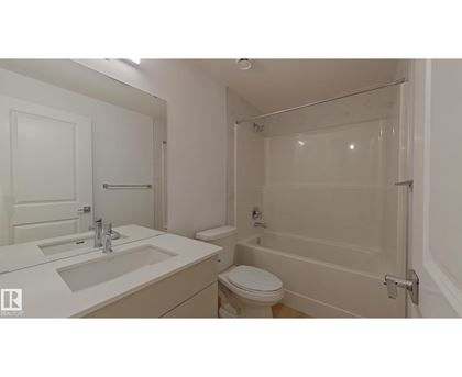 A white bathroom with a toilet, sink, and bathtub.