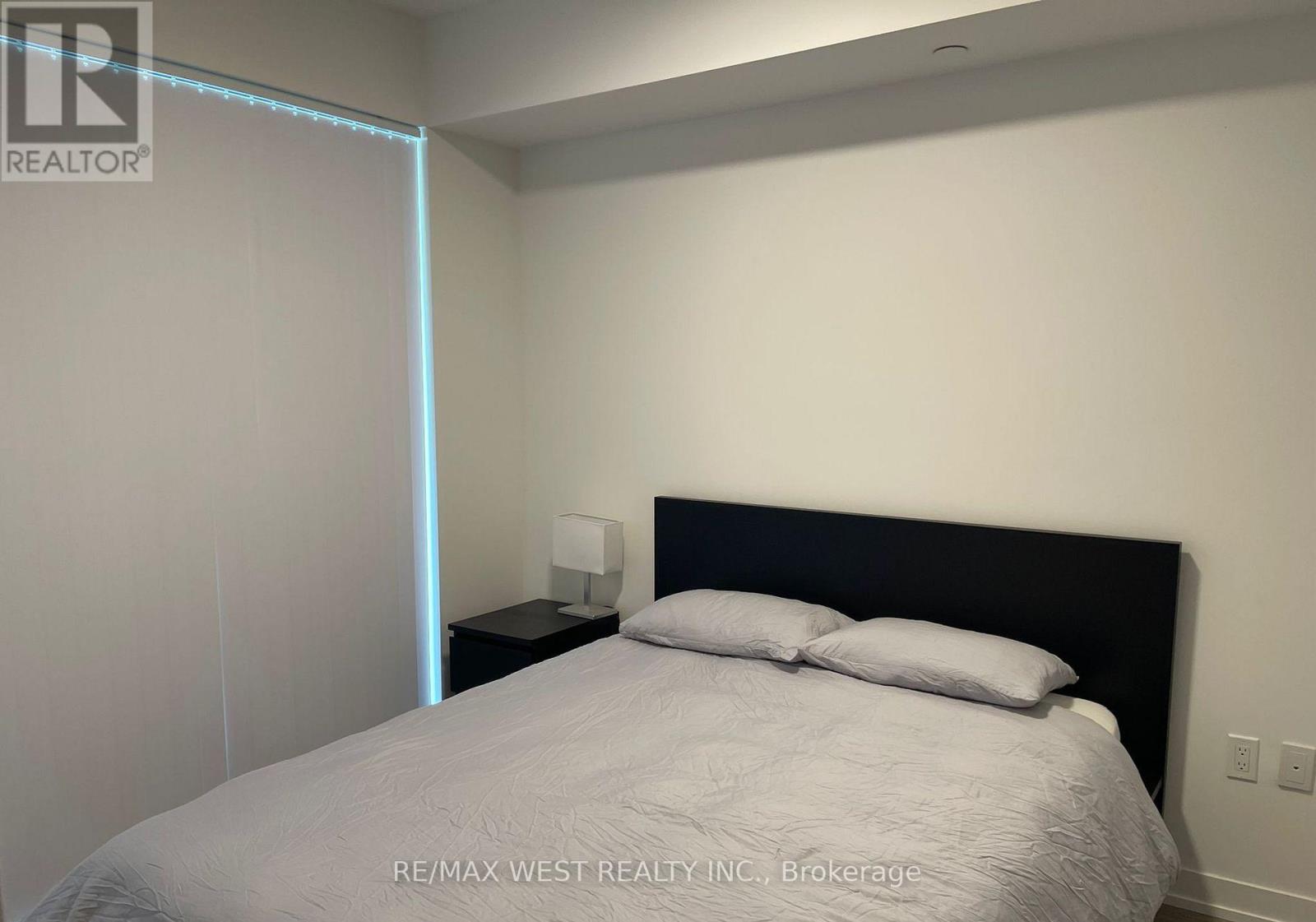 A bedroom with a bed, nightstand, and lamp.