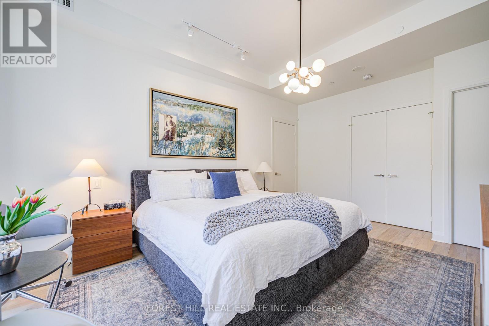 A bedroom with a large bed and a painting on the wall.